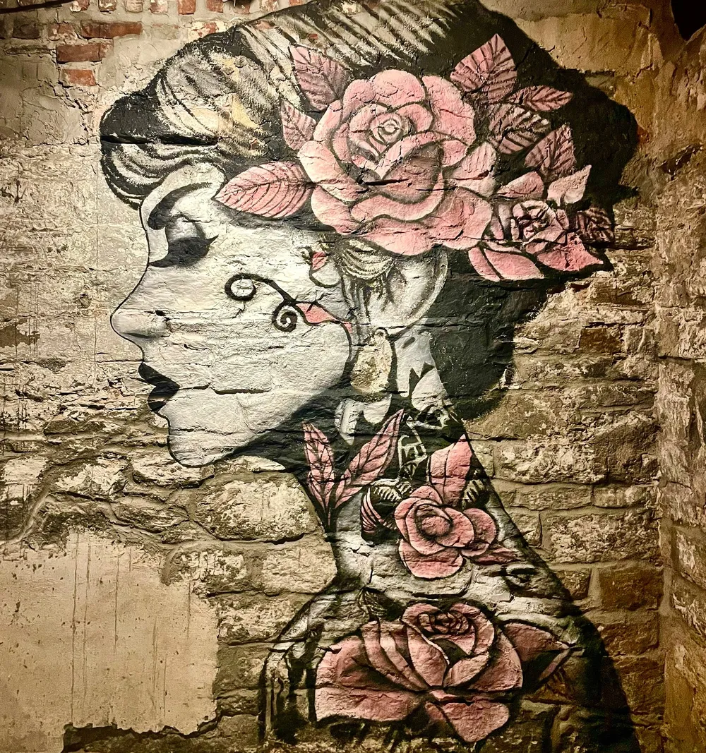 Portrait mural of a woman framed by roses on brick