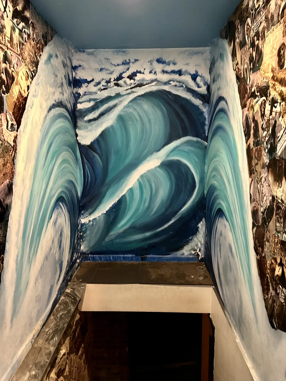 Teal ocean-wave mural painted in a stairwell